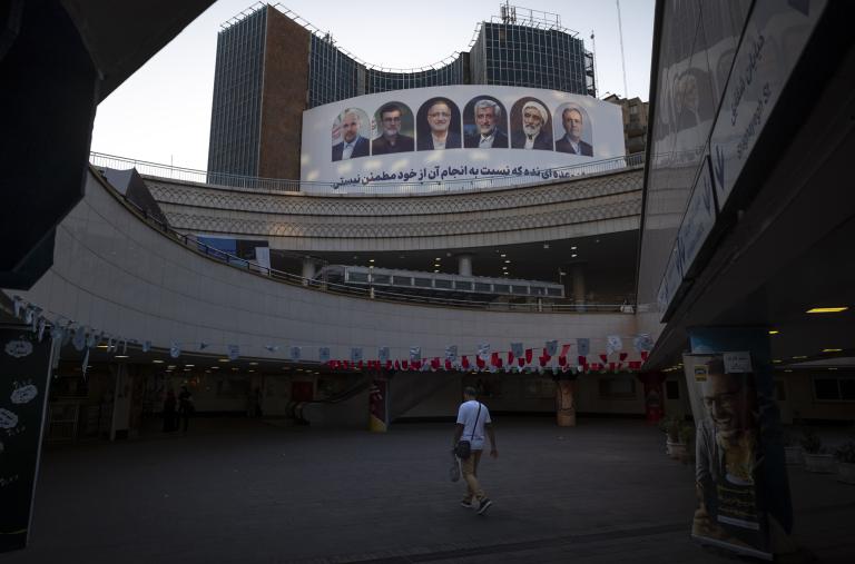 A man walks past a billboard in Tehran displaying candidates for president in Iran's emergency 2024 elections - source: Reuters