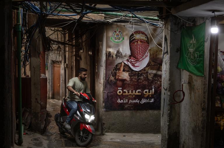 A man rides a scooter by a Hamas poster in a Palestinian refugee camp in Lebanon, May 18, 2024.