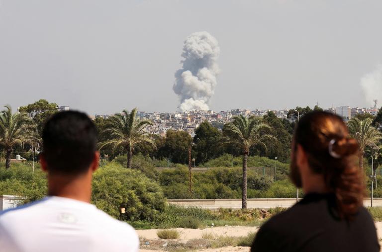 Men watch as smoke rises after an Israeli bombing of Hezbollah sites in southern Lebanon in September 2024 - source: Reuters