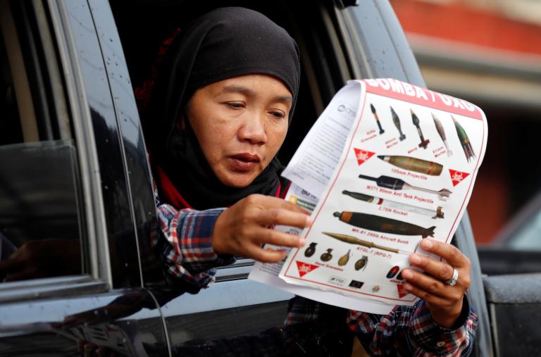 Photo of a woman reading a document at a military checkpoint in the Philippines before being permitted to return home after fighting between government troops and Islamic State militants.