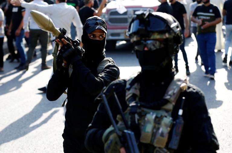 Armed members of the Iraqi Shiite militia Asaib Ahl al-Haq demonstrate at a funeral in Iraq - source: Reuters