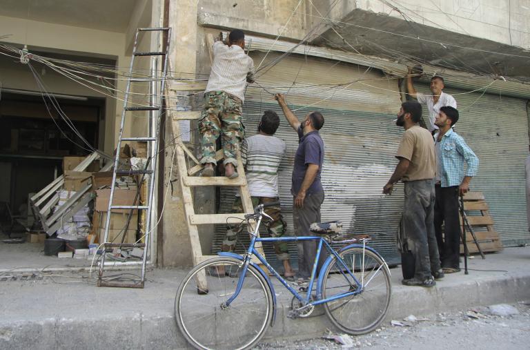 Syrian men attempt to repair electrical lines damaged by forces loyal to the Assad regime in 2013 - source: Reuters