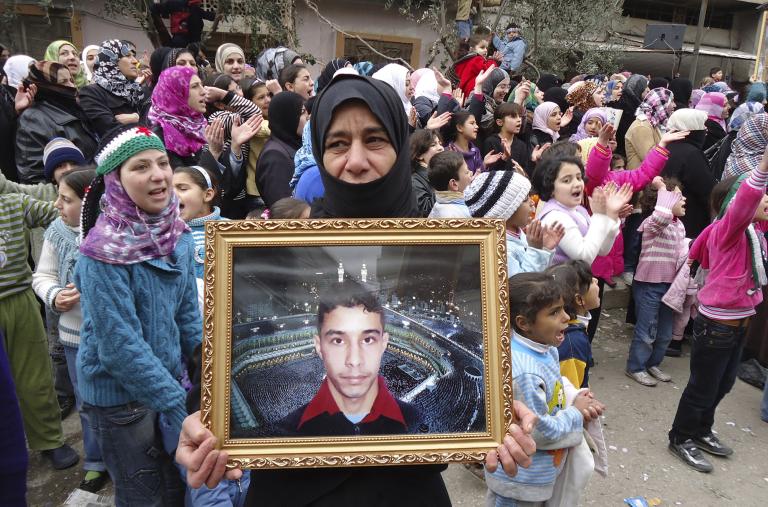 A Syrian woman holds a portrait of her missing son during a protest against the Assad regime in 2012 - source: Reuters