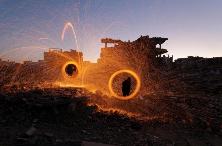 Photo showing Gaza residents spinning sparklers at the start of Ramadan, March 2025.