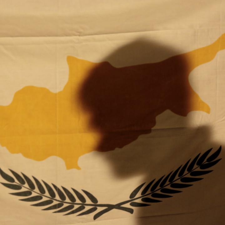 A protester's shadow falls across the flag of the Republic of Cyprus - source: Reuters
