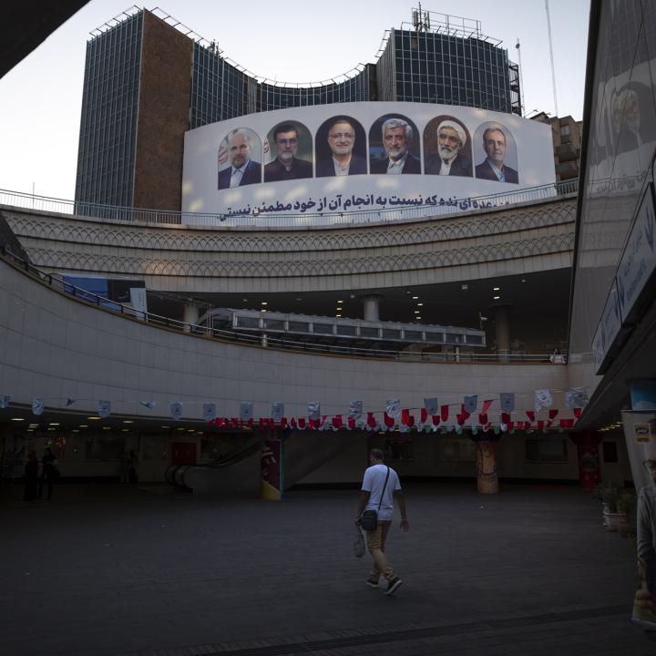 A man walks past a billboard in Tehran displaying candidates for president in Iran's emergency 2024 elections - source: Reuters