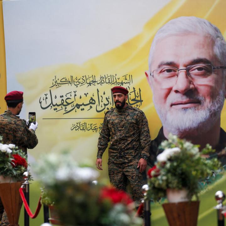 A Hezbollah fighter has his picture taken alongside a mural depicting deceased Hezbollah military leader Ibrahim Aqil at Aquil's funeral in September 2024 - source: Reuters