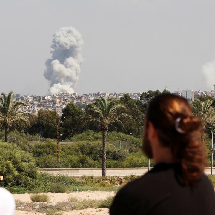 Men watch as smoke rises after an Israeli bombing of Hezbollah sites in southern Lebanon in September 2024 - source: Reuters