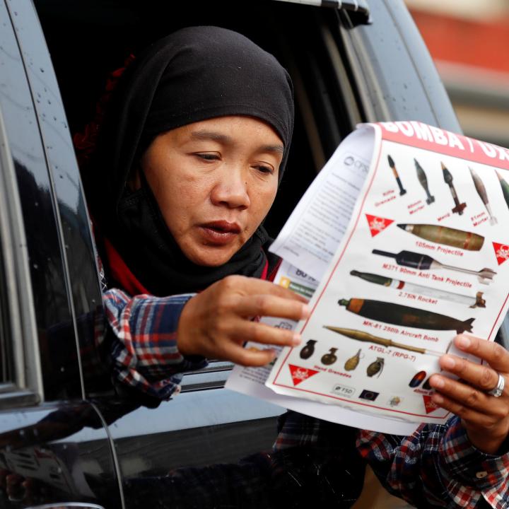 Photo of a woman reading a document at a military checkpoint in the Philippines before being permitted to return home after fighting between government troops and Islamic State militants.