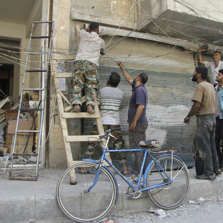 Syrian men attempt to repair electrical lines damaged by forces loyal to the Assad regime in 2013 - source: Reuters