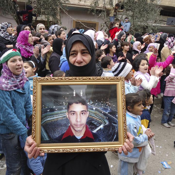 A Syrian woman holds a portrait of her missing son during a protest against the Assad regime in 2012 - source: Reuters