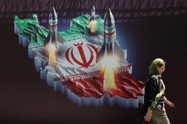 Photo of a woman walking in front of a mural that shows missiles being launched from Iran.