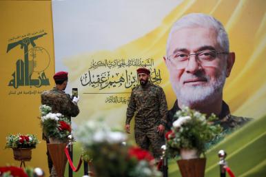 A Hezbollah fighter has his picture taken alongside a mural depicting deceased Hezbollah military leader Ibrahim Aqil at Aquil's funeral in September 2024 - source: Reuters