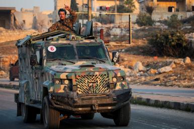 A rebel fighter belonging to the Islamist group Hayat Tahrir al-Sham gestures while riding a vehicle near Aleppo in November 2024 - source: Reuters