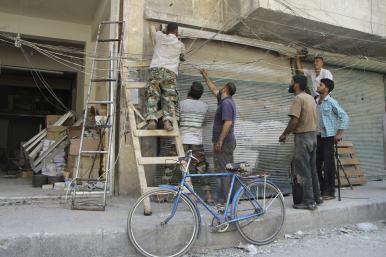 Syrian men attempt to repair electrical lines damaged by forces loyal to the Assad regime in 2013 - source: Reuters