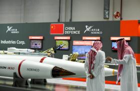 Men stand next to exhibits at the International Defence Exhibition in Abu Dhabi - source: Reuters